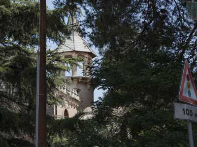 Spicca sul tetto la particolare la torre con guglia che svetta fra gli alberi